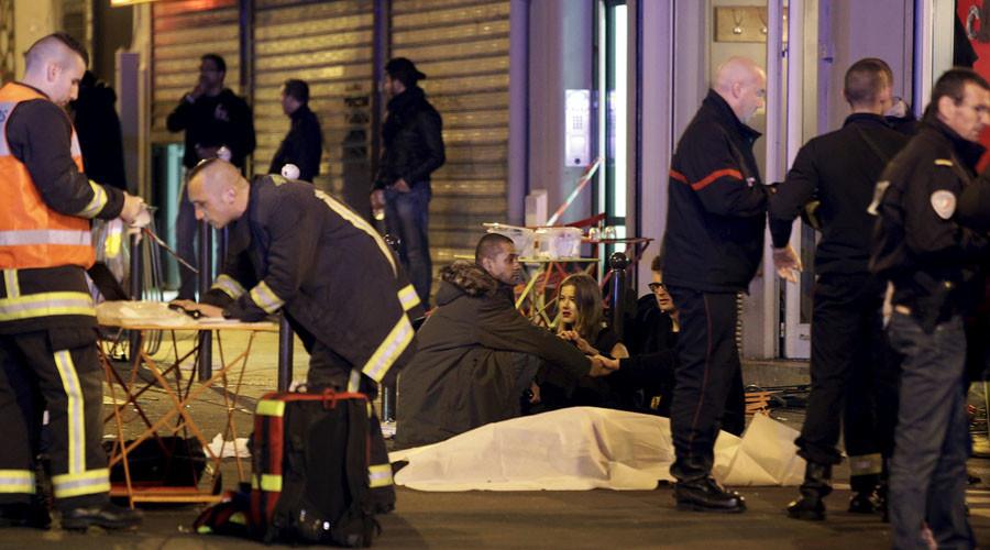 General view of the scene that shows rescue services personnel working near the covered bodies outside a restaurant following a shooting incident in Paris